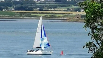 view of sail boat on water in front of golf course